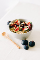a bowl of healthy Breakfast with oatmeal, figs and cashew nuts on a white table with a bamboo spoon. vegan food