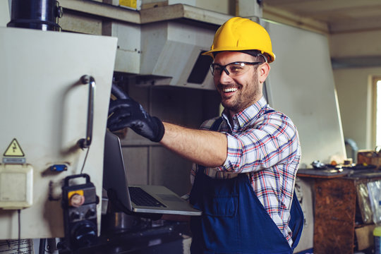 Industry Worker Entering Data In CNC Machine At Factory.