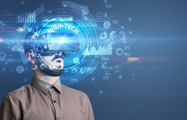Businessman looking through Virtual Reality glasses with HIGH-TECH inscription, innovative technology concept
