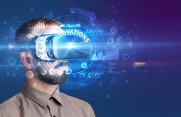 Businessman looking through Virtual Reality glasses with INNOVATIONS inscription, innovative technology concept
