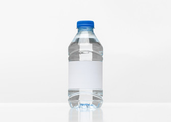 Plastic bottle with cap and white blank label isolated on white background.