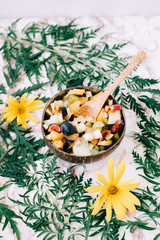 healthy fruit salad in a plate of coconut shells on the table with tropical leaves. vegetarian food