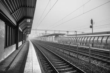 Black and white photo of an empty railroad station on a foggy day.