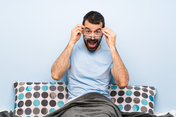 Man in bed with glasses and surprised