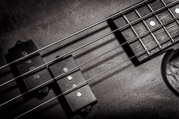 Bass guitar with four strings in black and white closeup. Detail of popular rock musical...