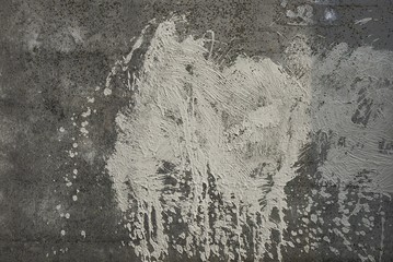 large white spot of paint on an old gray concrete fence wall