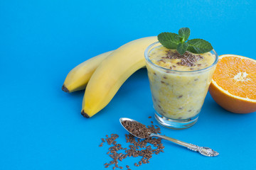 Smoothies with flax seeds, orange and banana  in the glass on the brown wooden  background. Copy...