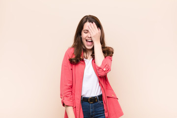 young pretty woman laughing and slapping forehead like saying d‚Äôoh! I forgot or that was a...