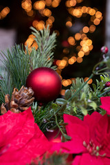 Rote Weihnachtskugel mit Tannenzweigen und Lichtbokeh im Hintergrund