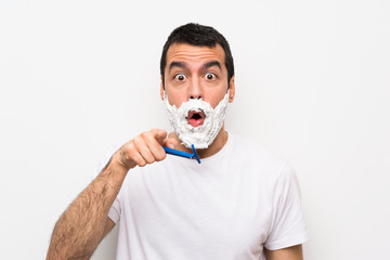 Man shaving his beard over isolated white background surprised and pointing front