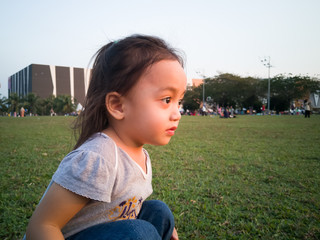 Fototapeta premium Asian toddler sit on the grass in the park.