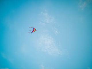 Colorful kite flying in the wind blue sky.