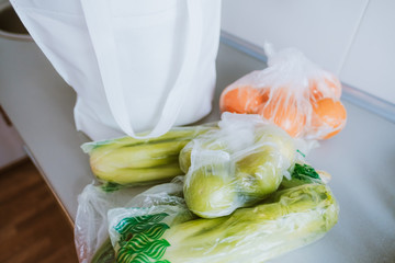 White eco bag with spread out fruits and vegetables on a table.
