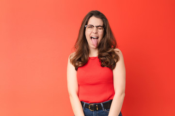 young pretty woman with cheerful, carefree, rebellious attitude, joking and sticking tongue out,...