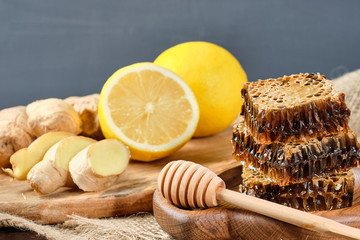Naklejka na ściany i meble honey in honeycombs on a wooden plate and honey with nuts with lemon and ginger in rustic style on a wooden background.