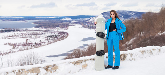 Portrait of a Young beautiful brunette woman with a snowboard