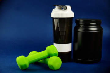 Protein in a black jar, plastic shaker, green dumbbells and omega-3 cans on a blue background
