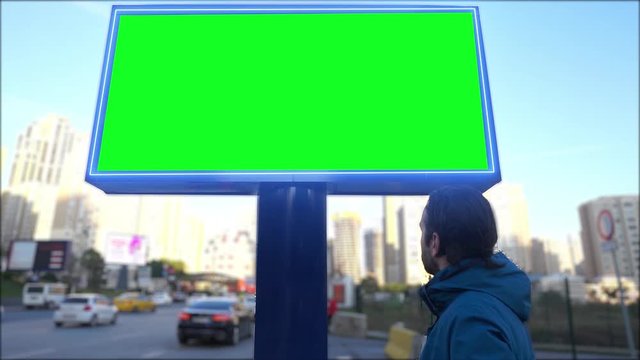 Green screen billboard on urban, street traffic. Cars are going and empty, blank chroma key signboard for marketing. 