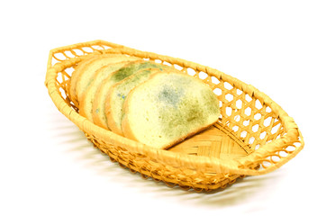 several slices of bread covered with mold lie in a basket isolated on a white background