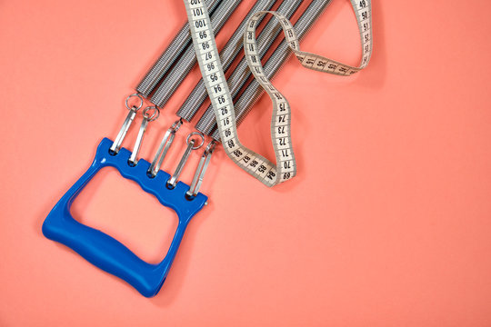 Espander spring with blue handle on pink background