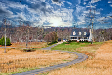 A nice white farmhouse down a long driveway across winter lawn