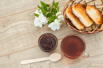 Glass cup of tea, bread, strawberry jam with white jasmine flowers