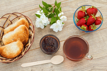Glass cup of tea, bread, strawberries with white jasmine flowers