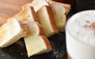 Toast arranged on a black plate with icing sugar.