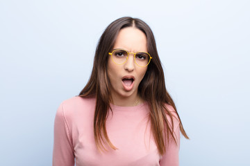young pretty woman looking shocked, angry, annoyed or disappointed, open mouthed and furious...