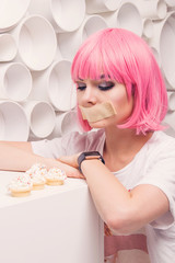 the diet concept. sad girl with taped mouth looking to sweets