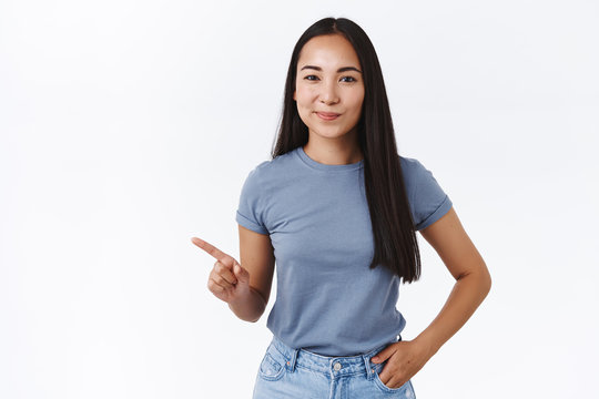 Sassy Good-looking Confident Brunette Asian Female Giving Advice What Product Pick, Showing Best Choice, Pointing Left, Smirk Satisfied Give Knowing Look, Hold Hand In Jeans Pocket, White Background