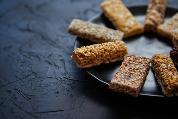 Different kind of granola fitness bars placed on black ceramic plate on a table