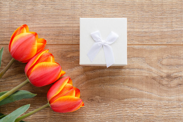 Gift box with red tulips on wooden boards.