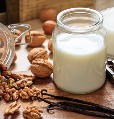 Walnut milk on a wood table. Nuts and glass with milk, non dairy milk for vegans and vegetarians