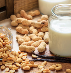 Peanut milk on a wood table. Nuts and glass with milk, non dairy milk for vegans and vegetarians