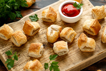 Pork sausage rolls with mustard and ketchup sauce on wooden board
