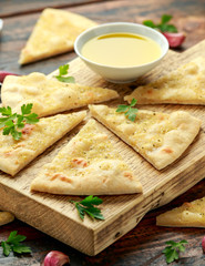 Fresh slices of Garlic pizza on wooden board with herbs.