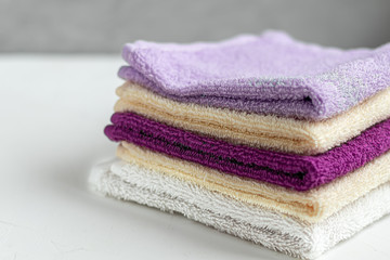 Terry towels for beauty and health. A stack of multi-colored towels lies on a white background....