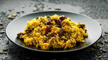 Morrocan style fruit couscous salad with raisins, dried apricots and pumpkin seeds on dark background