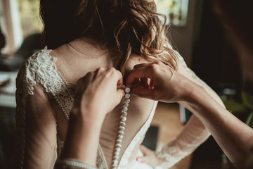Young bride getting ready for ceremony. Dressing up white wedding dress. Preparation background.