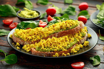 Scrambled Tofu crispy Toast with guacamole and spinach, tomato salad. Vegan vegetarian, plant based food
