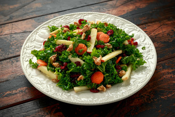 Kale salad with dried cranberry, carrots, walnuts and apple. healthy vegan food.