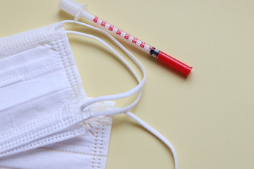 protective masks on a yellow background and syringe