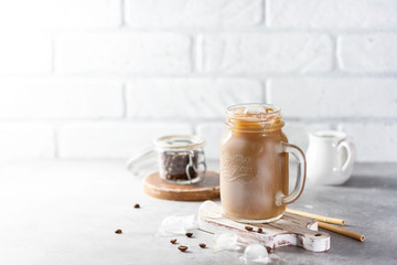 Ice coffee with milk and ice in a glass jar on a light background. Bamboo drinking straws with Zero - waste. Glass mason jar.