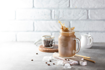 Ice coffee with milk and ice in a glass jar on a light background. Bamboo drinking straws with Zero - waste. Glass mason jar.