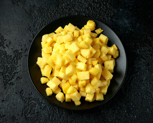 Fresh juicy pineapple slices on black plate. rustic background