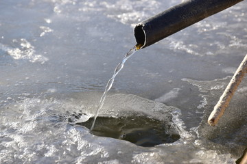 acqua che scorre da un tubo di un abeveratoio ghiacciato