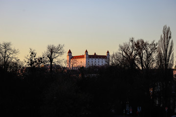 Fototapeta premium Castillo blanco de Bratislava entre los árboles al atardecer.