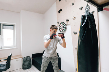 16-17 years old teenage boy workout with boxing bag in home gym room
