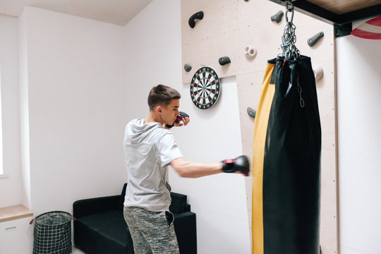 16-17 Years Old Teenage Boy Workout With Boxing Bag In Home Gym Room